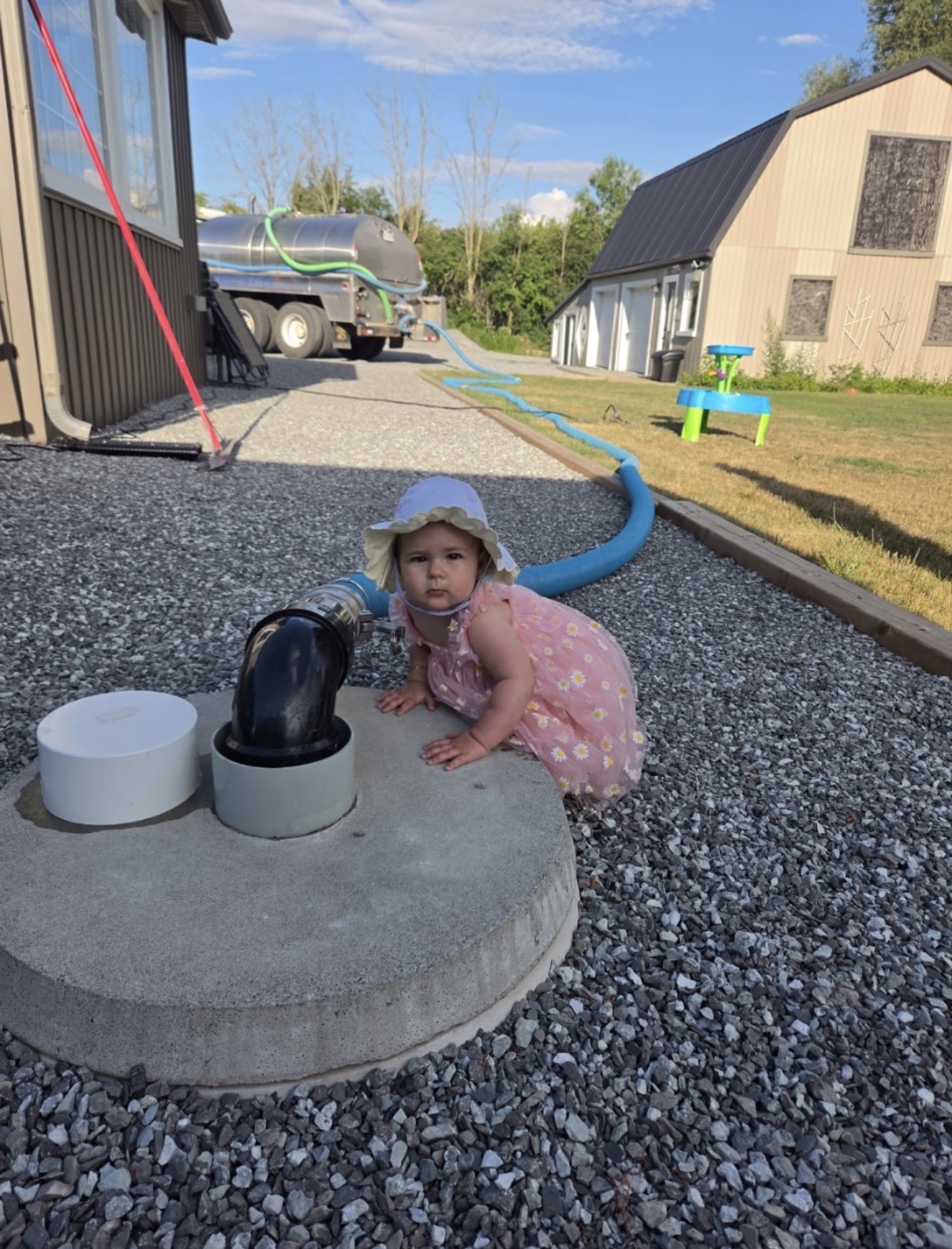Child crouching beside a water delivery hose connection during a delivery