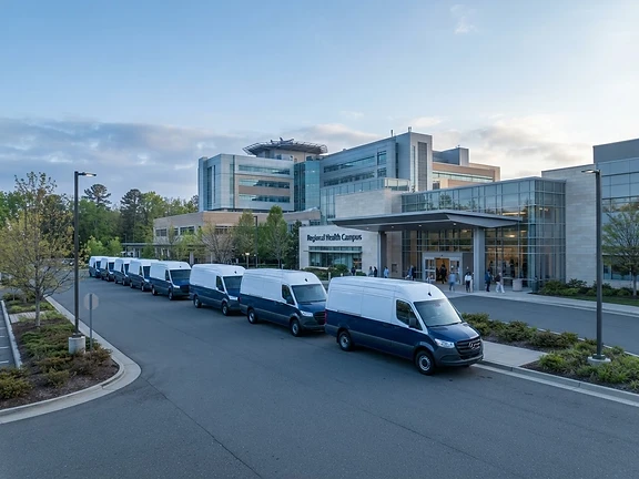 Fleet of delivery vans parked outside a healthcare campus