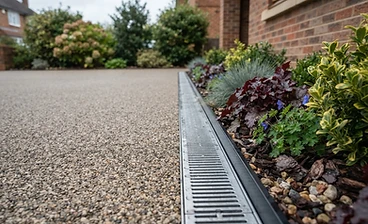 Resin driveway meeting a drainage channel and planted border