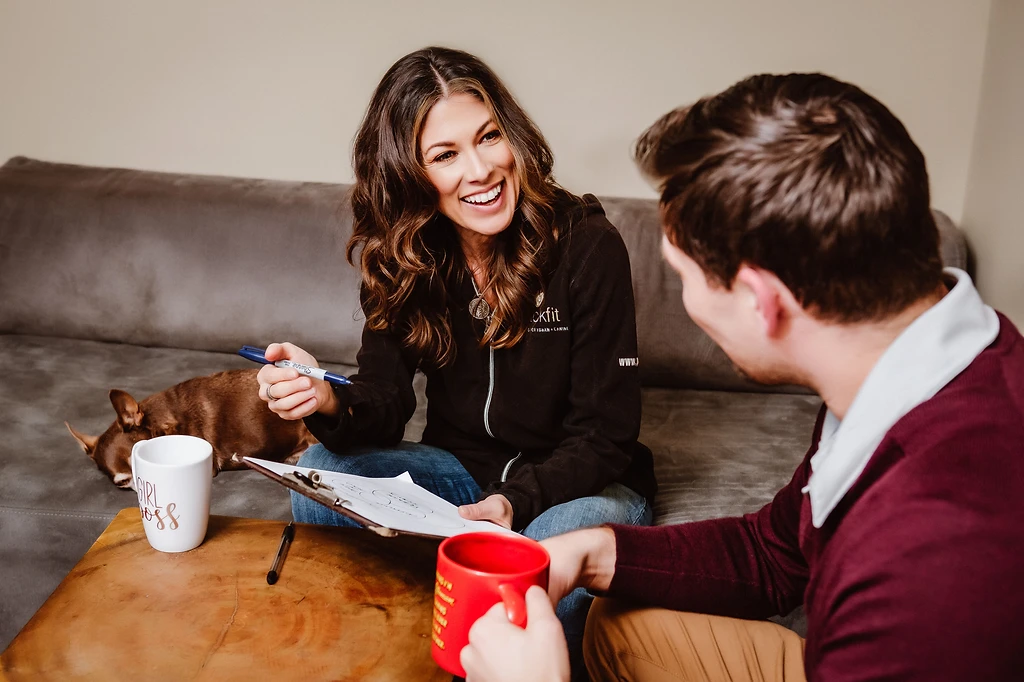 Kimberly Artley during a behavioral consultation with a client, seated on a couch with a dog resting nearby