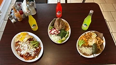 Top-down table of chilaquiles, carnitas, and steak with Jarritos at El Alex