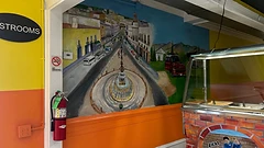 Wall mural of a town plaza with fountain and red truck