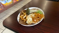 Bistec with two sunny-side-up eggs, beans, onions, and avocado