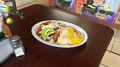 Chilaquiles rojos topped with queso fresco, crema, avocado, and a fried egg
