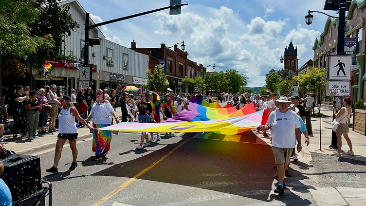 Pride Halton 2025 parade marching down Main Street Milton with the Progress Pride flag