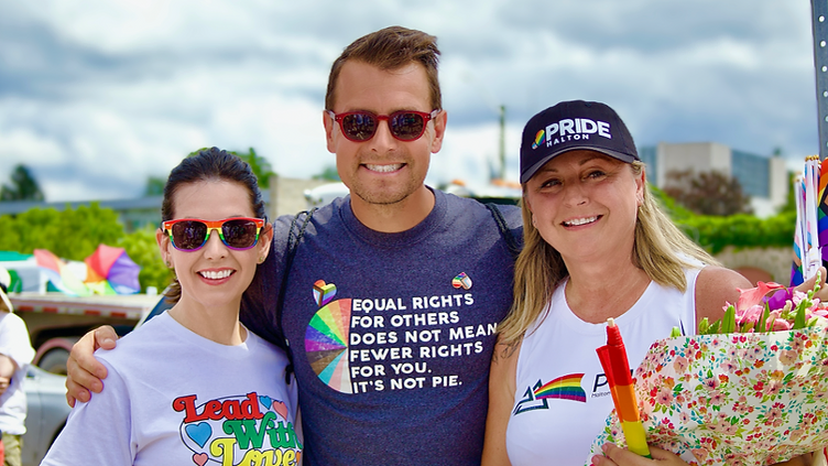 Pride Halton founder Melanie Tremills (centre, holding flowers) with Members of Parliament Kristina Tesser Derksen (left) and Adam van Koeverden (right) at a Pride Halton celebration