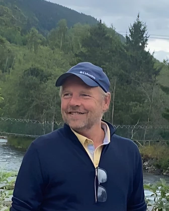 Johan Janssens in de natuur, aan een rivier met groene heuvels