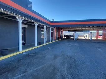 Commercial drive-through facility with charcoal walls and orange accent trim, commercial exterior painting in Odessa, TX