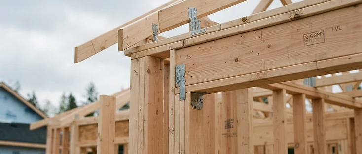 Clean wood framing of a small residential suite under construction against an overcast Edmonton sky