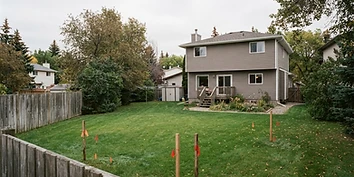 Edmonton residential backyard with survey stakes marking open space at the rear of the lot