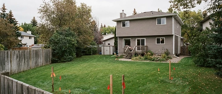Edmonton residential backyard with survey stakes marking the open space at the rear of the lot