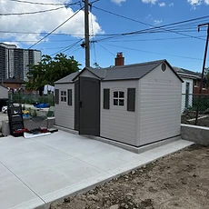 A finished light gray resin shed installed on a clean concrete pad.