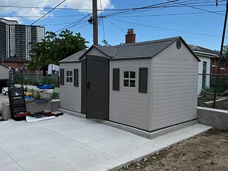 A finished light gray resin shed installed on a clean concrete pad.