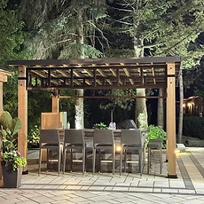 Assembled wooden pergola standing over a backyard patio with garden landscaping.