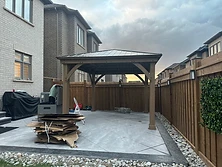 A completed wooden pergola installed on a stone patio.