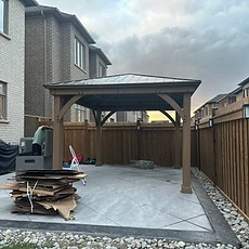 A completed wooden pergola installed on a stone patio.