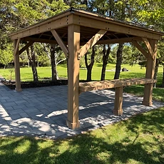 A wide angle view of an installed black metal pergola over a patio dining area.