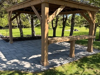 A wide angle view of an installed black metal pergola over a patio dining area.