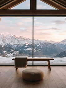 Chalet de bois face aux sommets enneigés au lever du jour
