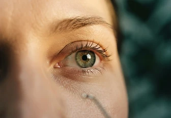 Editorial close-up of a human eye bathed in warm golden and teal light