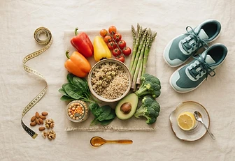 Flat-lay of fresh vegetables, whole grains and running shoes on cream linen