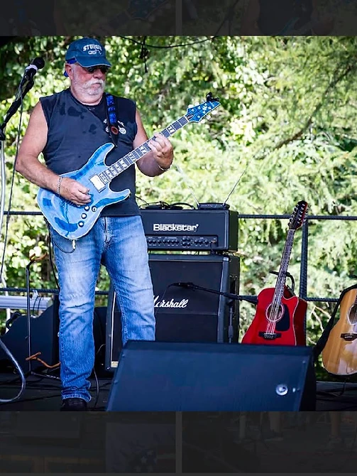 Guitarist playing a blue electric guitar on the outdoor stage