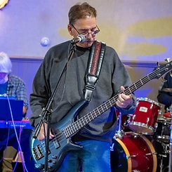 Bass player mid-strum on a black bass with a tooled leather strap