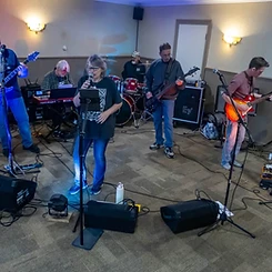 Six-piece band rocking an indoor stage under mixed colored lighting