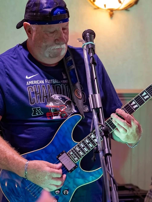 Guitarist laying down a solo on a blue Schecter under cool stage light