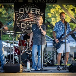 Over and Out on stage at sunset under the gazebo banner