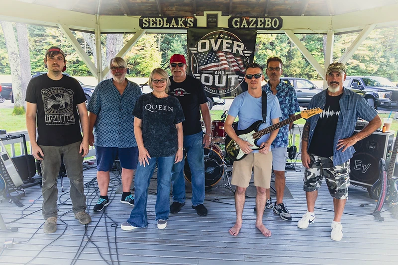 Over and Out band posing in a gazebo with their banner