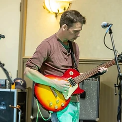 Guitarist playing a cherry sunburst Les Paul under teal stage light