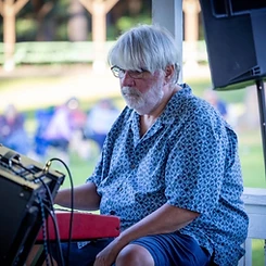Keyboardist playing a red Nord keyboard on the gazebo stage
