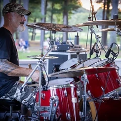 Drummer playing a red Pearl kit under the gazebo