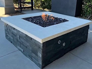 Square stacked-stone fire pit with concrete cap on a concrete patio