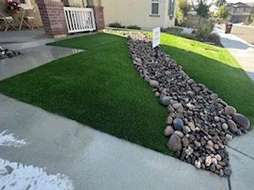 Artificial turf front yard with decorative dry creek bed and concrete walkway