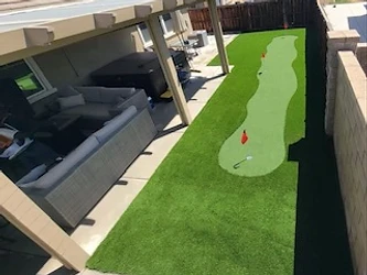 Artificial turf putting green with flags beside a covered concrete patio