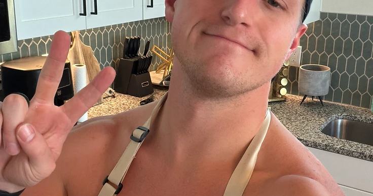 Devin Goff in his kitchen wearing an apron, smiling