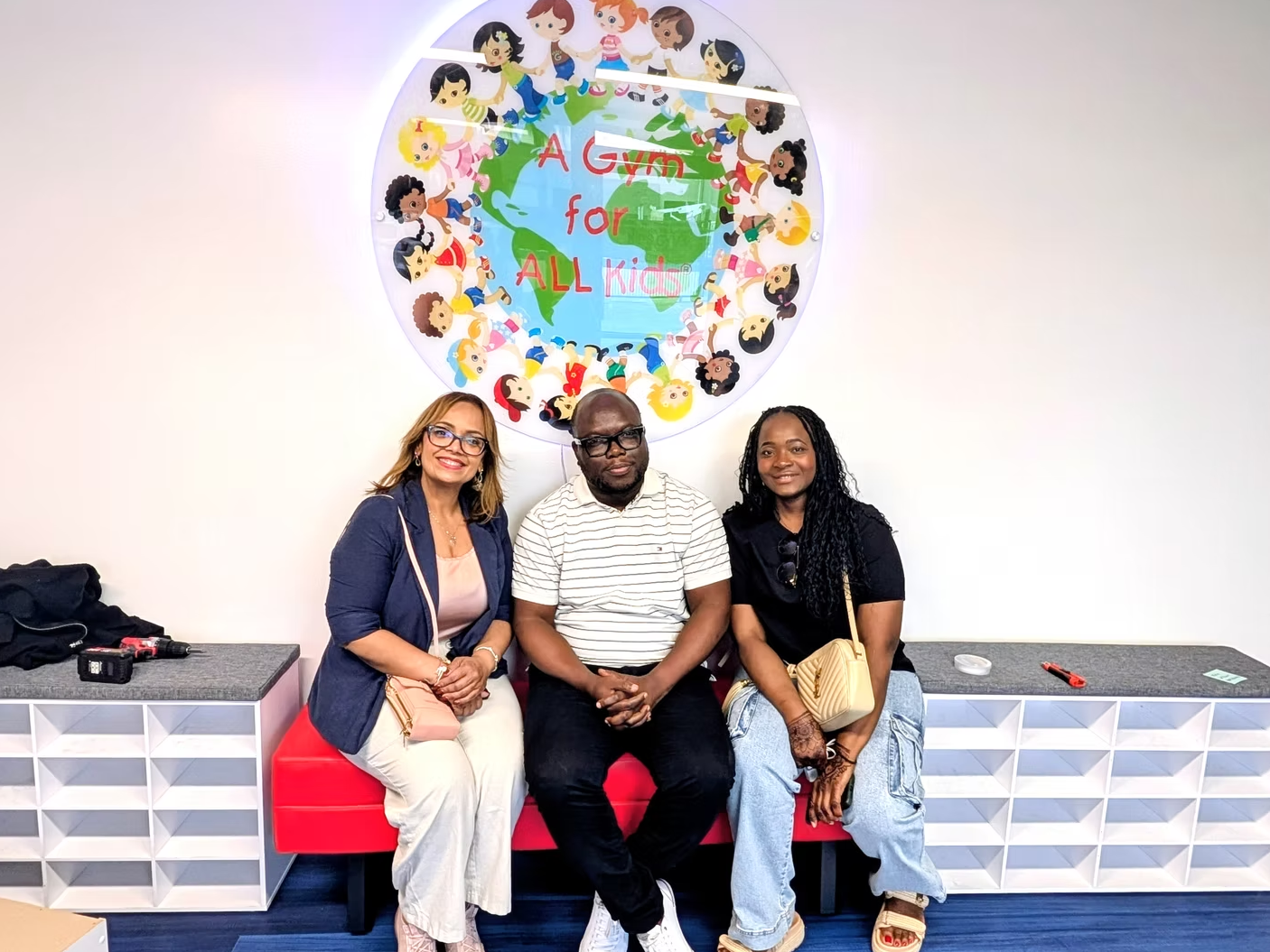 Waiver Group consultants seated beneath the "A Gym for All Kids" mural