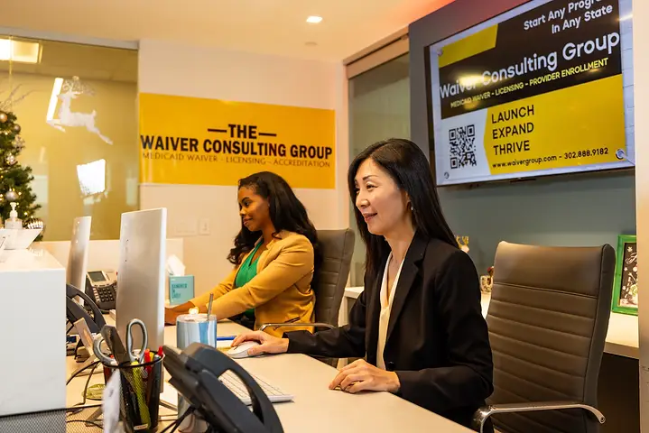 Two Waiver Consulting Group specialists working provider enrollment files at their desks