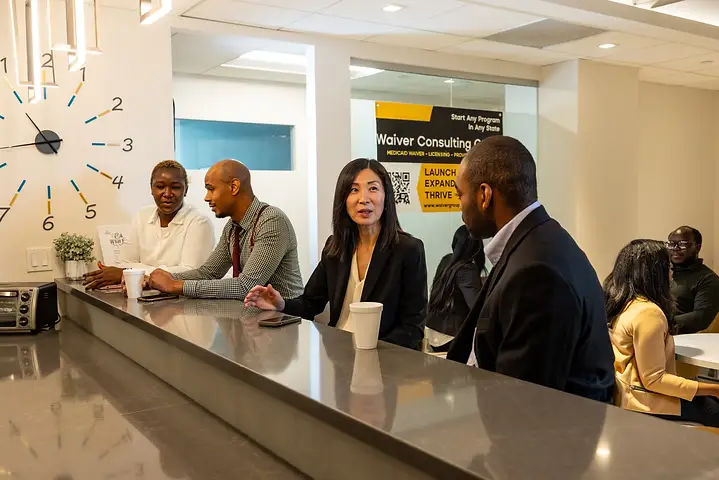 Waiver Consulting Group consultants talking with clients along the office counter