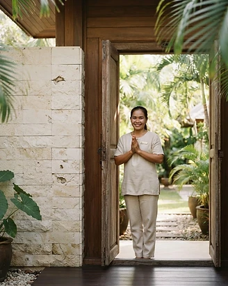 Warm villa host greeting guests at an open Koh Samui villa at golden hour