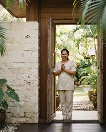 Welcoming villa host at an open Koh Samui villa entrance at golden hour