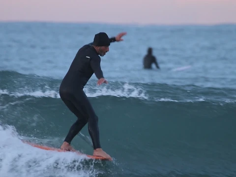 Aprender longboard em Vila do Conde: o Gaio a deslizar numa onda durante uma aula de longboard clássico
