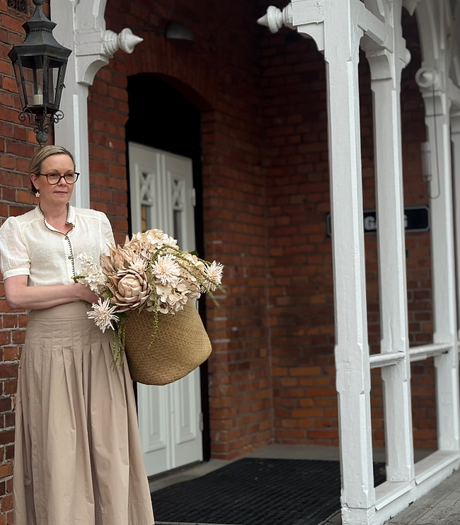Veronica med korg och blommor utanför butiken i Lyckeby