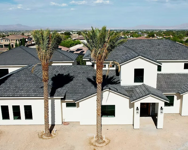 Completed charcoal shingle roof installation with desert landscape