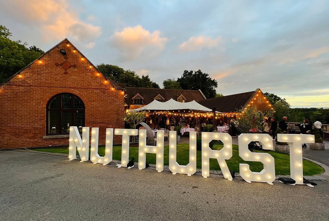 NUTHURST marquee letters at a twilight garden event