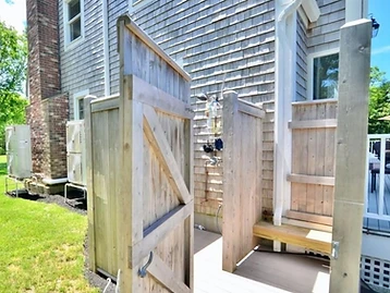Outdoor cedar shower enclosure against the shingled house exterior