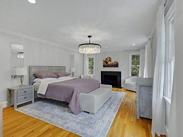 Primary suite with purple coverlet, black fireplace, and crystal chandelier