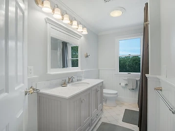 Bathroom with grey vanity, framed mirror, and white wainscoting